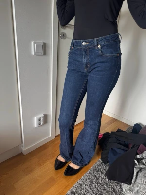 Mörkblå raka jeans med hög midja - Säljer ett par mörkblå jeans med rak passform och hög midja. Klassisk femficksmodell med knapp och dragkedja framtill. Jeansen har långa ben och är tillverkade i ett denimtyg med lätt stretch. Perfekta till sneakers eller boots.
