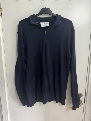 Mörkblå halvzip från Selected Homme - Snygg mörkblå långärmad tröja från Selected Homme med halvzip och ståkrage. Tillverkad i mjukt material som känns skönt mot huden. Perfekt för dig som gillar stilrena och enkla plagg med en modern touch. Perfekt skick!