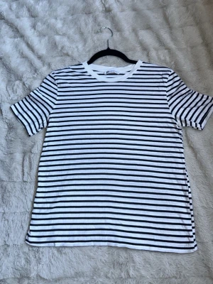 Randig t-shirt från Zara  - En klassisk vit t-shirt med svarta horisontella ränder från Zara. T-shirten har rund halsringning och korta ärmar. Perfekt för en avslappnad och stilren look. Tillverkad i mjuk bomull som känns skön mot huden.  Finns små tecken på användning men inget som stör dess funktion eller syns om man inte är suuuuper petig, men kan bekämpas med rätt medel för den händiga🤍