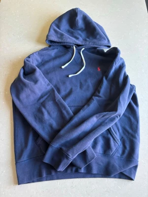 Mörkblå hoodie från Polo Ralph Lauren - Snygg mörkblå hoodie från Polo Ralph Lauren i bra skick, nypris på denna pärlan ligger på upp till 2300kr! Detta ärmen bekväm hoodie som är perfekt å ha på sommarkvällar när solen går ner eller på kyligare dagar!🌅Hör av dig vid funderingar!! (Pris går såklart att diskutera)
