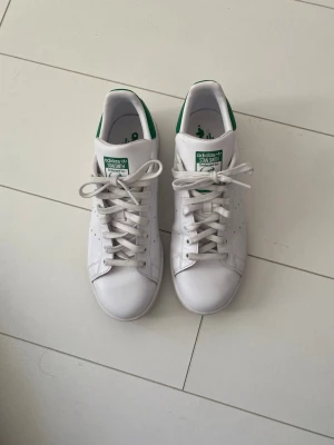 Adidas Stan Smith vita sneakers - Adidas Stan Smith sneakers i vitt med gröna detaljer. Endast använda 3 gånger så i väldigt bra skick! 