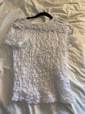 Vit spetsblus med kort ärm - Säljer en söt vit blus i spets med korta ärmar. Blusen har ett genombrutet mönster och är perfekt för dig som gillar romantisk och feminin stil. Passar till både jeans och kjol. Superfin detalj med spets över hela toppen.