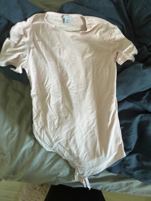 Ljusrosa body från new yorker - En enkel och stilren ljusrosa body från new yorker med korta ärmar och rund halsringning. Tillverkad i mjukt material som känns skönt mot huden. Perfekt att matcha med jeans eller kjol för en clean look.