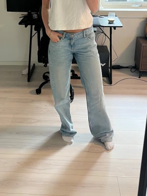 Ljusblåa raka/vida jeans med låg midja - Säljer ett par ljusblå jeans med rak passform och låg midja. Jeansen har klassisk femficksdesign och är tillverkade i denim. Perfekta för en avslappnad och trendig look.