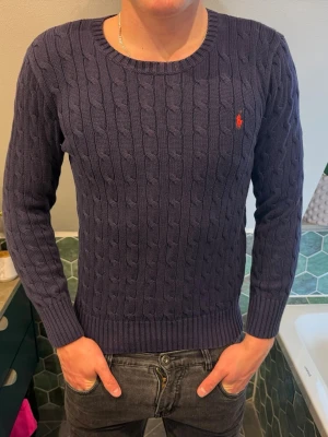 Mörkblå kabelstickad tröja Polo Ralph Lauren - Snygg mörkblå kabelstickad tröja från Polo Ralph lauren. Lite för liten på mig därav passformen. Storlek L men sitter som en S/Xs! 
