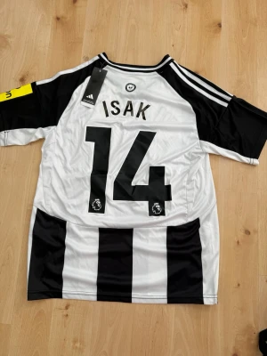 Isak #14 – Fan Edition (storlek S) - Isak #14-tryck. Fan Edition. Storlek S. Helt ny och aldrig använd. Säljs i befintligt skick. Skickas snabbt! 🚚💨  Mått för denna tröja (storlek S): (Uppmätta av leverantör – viss variation kan förekomma) • Halva bröstmåttet: 51 cm • Tröjans längd: 71 cm • Ärmbredd: 22 cm • Axelbredd: 42 cm • Ärmlängd: 38 cm • Manschettbredd: 18 cm  🔥 Fan Edition – normal/mer avslappnad passform.