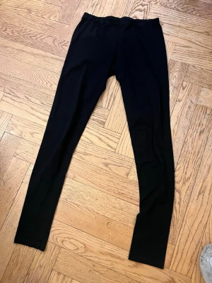 Svarta klassiska leggings - Svarta leggings med hög midja och smal passform. Mjukt och stretchigt material som sitter skönt mot kroppen. Perfekta att matcha med oversized tröjor eller hoodies. Inga synliga detaljer eller loggor.