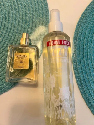 Memory No. 520 parfym & 777 Eau de Cologne - Säljer två parfymer: Memory Fragrance No. 520 i en fyrkantig glasflaska med guldfärgad etikett och spray, samt 777 Eau de Cologne i en genomskinlig plastflaska med blommönster och vit spraykork. Båda har en fräsch och elegant design.