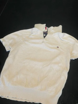 Vit kortärmad skjorta Tommy Hilfiger - Vit kortärmad skjorta från Tommy Hilfiger med diskret strukturmönster och klassisk krage. Små knappar framtill och broderad logga på bröstet. Perfekt till sommarens alla outfits.