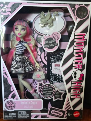 Monster High , Boo-riginal creeproduktion - Monster High docka Rochelle Goyle Boo-riginal Creeproduction i originalförpackning. Dockan har rosa och blått hår, vingar, svartvit klänning med mönster, och medföljer väska, dagbok och figur. Förpackningen är svart och rosa med Monster High-logga.