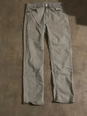 Ljusgrå raka jeans - Säljer ett par ljusgrå jeans med rak passform och klassisk femficksdesign. Jeansen har knappgylf och är tillverkade i ett mjukt denimtyg som ger en avslappnad look. Perfekta för dig som gillar stilrena och enkla basplagg.