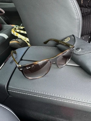 Ray-Ban bruna solglasögon Wayfarer - Snygga Ray-Ban Boyfriend solglasögon i brunmelerad plast med mörka glas. Klassisk modell med Ray-Ban-logga på linsen och robust båge. Perfekta för soliga dagar och kommer med originalfodral.