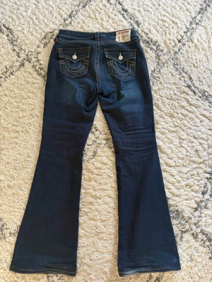 Mörkblå bootcut jeans True Religion - Säljer ett par mörkblå mide Rise bootcut jeans ifrån True Religion eftersom dom är för stora. Jeansen är uppsydda ungefär 5 cm. Priser går att diskutera 