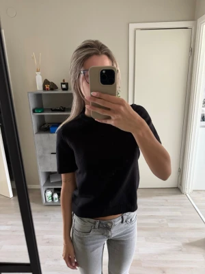 Svart croppad topp med kort ärm - En enkel och stilren svart croppad topp med korta ärmar och rund hals från Gina. Mjuk och bekväm.