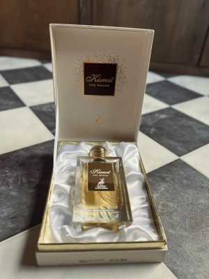 Kismet For Women Eau de Parfum 100ml - Lyxig parfym för kvinnor från Maison Alhambra, Kismet For Women. Kommer i en elegant, genomskinlig glasflaska med guldig kork och exklusiv vit presentask med satinliknande insida. Doften är sofistikerad och flaskan har en stilren, rektangulär form. Bara testad. 