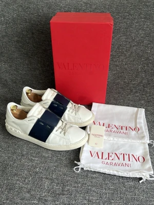 Valentino Open navy  - Hej, Valentino Garavani skor i helhet gott skick. Skolåda, 2st dustbags och kort medföljer i köpet. Sulorna är slitna och har kickats moppe med några gånger men annars är dessa i bra skick. Självklart autentiska vilket jag står för. Nyvärde 7200kr. Hör gärna av dig!