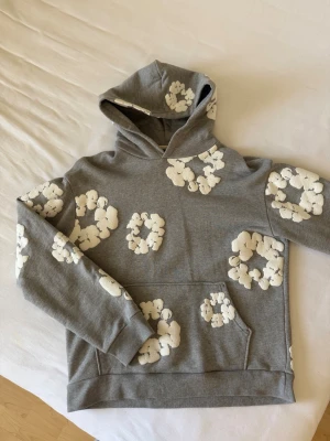 Grå hoodie med vita blommor Denim Tears - Säljer en grå hoodie från Denim Tears. Hoodie är köpt i New York och är äkta direkt från butik. Denim tears är grundat i nyc och där med har butik över staden. Hoodie är i mkt god skik samt strlk L
