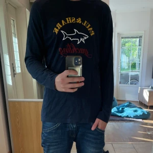 Tröja Paul & Shark 🇮🇹 - Säljer en mörkblå långärmad tröja från italienska märket Paul & Shark 🇮🇹med tryck i gult, vitt och rött framtill. Tröjan har klassisk passform och är gjord i mjuk bomull. Perfekt för dig som gillar stilren design med sportig känsla och tydlig logga på bröstet.
