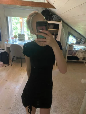 Svart kort klänning med snörning - Säljer en svart, tight kortklänning med snörningsdetalj i nederkanten. Klänningen har rund halsringning och korta ärmar. Säljes då den ej kommer till användning. Köpt på HM