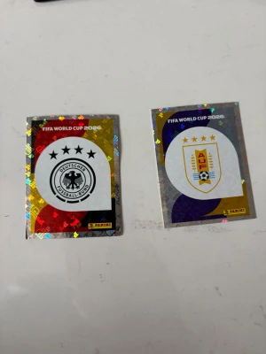 FIFA World Cup 2026 Panini stickers - Tysklands och Uruguays landslagsloggor. 
