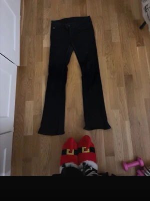 Svarta bootcut jeans från Weekday  - Säljer ett par svarta bootcut jeans från Weekday/cheap monday med klassisk femficksmodell och lila patch bak i midjan. Jeansen har låg midja och utsvängda ben, perfekta för en trendig och avslappnad look. Materialet är denim med stretch för extra komfort. Dom är i storlek 27/30.