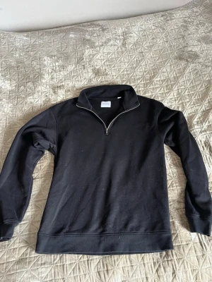 Svart halvzip  - Svart hoodie från Jack & Jones. Halv dragkedja framtill och hög krage. 