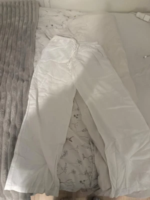 Vita linnebyxor  - Säljer ett par vita linnebyxor med avslappnad passform och dragsko i midjan. Byxorna har raka, vida ben och är tillverkade i ett lätt och luftigt linnematerial. Perfekta för en chill och stilren look. Från Gina tricot storlek 146/152. Som nya.