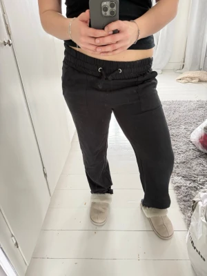 Svarta mjukisbyxor med dragsko - Säljer ett par svarta mjukisbyxor med bred resårmidja och dragsko. Byxorna har raka ben, stora fickor framtill och är gjorda i mjukt sweatshirtmaterial. Perfekta för chill dagar eller när du vill vara bekväm.