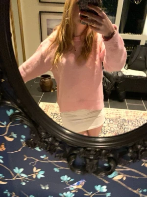 Ljusrosa stickad tröja - Mysig ljusrosa stickad tröja med rund hals och avslappnad passform. Tröjan har långa ärmar och en fluffig, mjuk struktur som ger en trendig och bekväm look. Perfekt att matcha med kjol eller jeans för en söt och enkel stil.