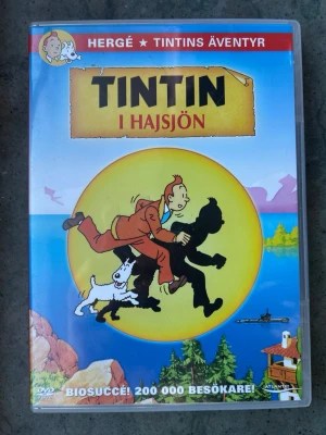 Tintin i hajsjön dvd - DVD-film med Tintin i Hajsjön. Filmen är från 1972 och har en speltid på 1 timme och 13 minuter. Ljudformatet är Dolby Digital Mono och bildformatet är 16:9 Anamorphic Widescreen (1.77:1). Svenska röster inkluderar John Harryson, Thomas Bolme, Kjerstin Dellert och Bert-Åke Varg.  Finns på språk: Svenska, Norska, Danska   OBS!! skivorna är begagnade så det kan förekomma repor/hairlines på skivorna, men då jag kollar igenom alla filmer jag säljer garanterar jag att alla funkar felfritt
