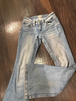 Ljusblå bootcut jeans med slitningar - Säljer ett par ljusblå lågmidjade bootcut jeans ifrån Gina Tricot, med fina detaljer på bakfickorna och dom är i storlek xs!