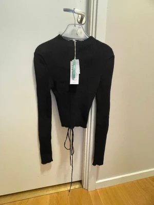 Svart stickad topp med snörning - Sjukt snygg topp från Gina. Har liksom en en cool design där bak i ryggen! Passar både till vardag och fest! Och sjukt bra till jeans på våren!!!!!! Säljer pga den nt passar annars fett snygg! ❤️😩prislappen sitter kvar! Köptes för 469kr
