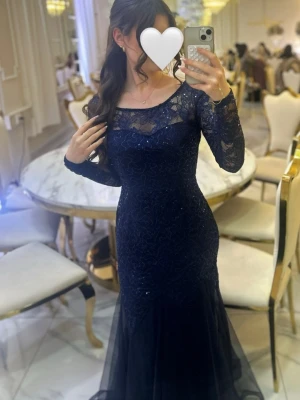 Marinblå långklänning med spets - Säljer en marinblå långklänning med figurnära passform och långa spets ärmar. Klänningen har vacker spets upptill och på armarna med glittriga detaljer som ger extra lyxig känsla. Den har en lätt utsvängd kjol i tyll. Perfekt för bal eller fest!🫶🏼 (endast använd 1 gång)