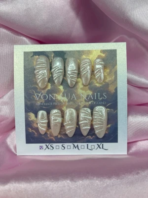 Glossy (XS);Medium Almond - Handgjorda press-on naglar i skimrande beige med vit swirl-design. Naglarna har en medium lång mandelformad stil och kommer i  XS: 14 mm, 11 mm, 11,5 mm, 10 mm, 8 mm . Perfekt för dig som vill ha unika och trendiga naglar utan att gå till salong.