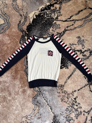 Randig stickad tröja med Union Jack - Snygg stickad tröja från PARKhande i vitt med marinblå muddar och ärmar. Ärmarna har röda och vita ränder och på bröstet samt ryggen finns Union Jack-flagga. Perfekt för dig som gillar en amerikansk och cool stil. Anledning till att jag säljer den är på grund av att jag börjar bli trött på den. 