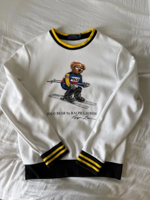 Vit sweatshirt Polo Bear Ralph Lauren - Vit sweatshirt från Ralph Lauren med Polo Bear-tryck framtill där björnen åker skidor. Endast använd 1 gång så väldigt bra skick. Storlek 170! 