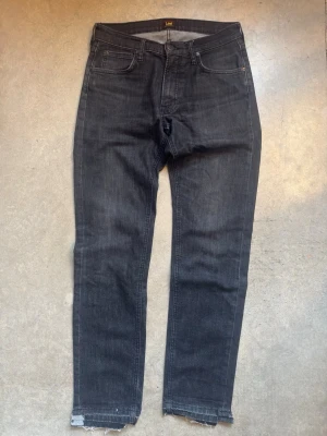 Lee jeans - Säljer ett par svarta jeans från Lee i organisk bomull. Modellen har klassisk femficksdesign, raka ben och rå, fransad kant nedtill för en trendig look. Perfekta för dig som gillar en avslappnad men ändå stilren stil.