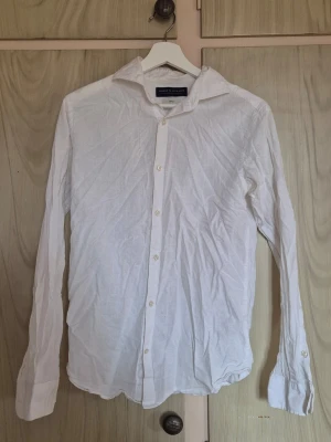 Vit skjorta - Klassisk vit skjorta från Jack & Jones  med lång ärm och knappar framtill. Skjortan har en enkel och stilren design med krage och är tillverkad i bomull. Perfekt för dig som gillar en clean och tidlös look. En av knapparna är halv men där finns extraknapp att byta till. Använd dåtal gånger.          Alla kläder rollas innan dom skickas hem då det finns katt i hemmet🐈 Jag stryker och tvättar INTE innan jag skickar det får du stå för själv så det blir som du vill ha det🤗