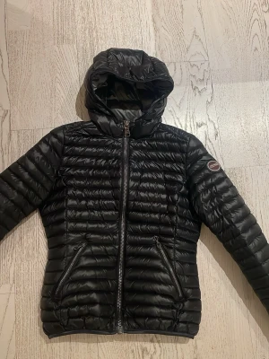 Svart dunjacka med huva från Colmar - Säljer en super snygg svart glansig dunjacka från Colmar med huva. Perfekt för våren och hösten. Jackan är mycket bra kvalitet och skick! Priset är diskuterbart, skriv vid minsta fundering.