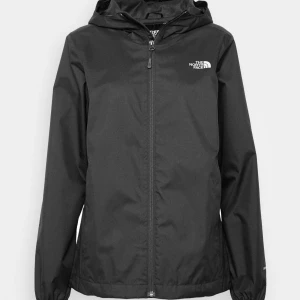 Svart regnjacka från The North Face - Snygg svart regnjacka från The North Face med huva och dragkedja framtill. Jackan har en stilren design med logga på bröstet och elastiska muddar vid ärmslut. Perfekt för blöta dagar och enkel att matcha med allt. Kontakta mig för egna bilder! 