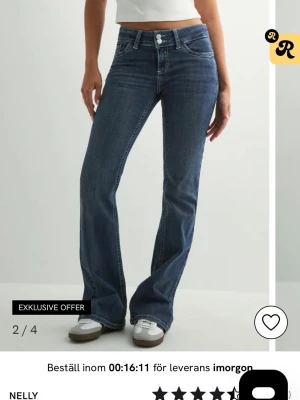 Blå bootcut jeans från Nelly - Bootcut jeans i mörkblå denim från Nelly med hög midja och klassiska fem fickor. Snygga kontrastsömmar och dekorativa detaljer på bakfickorna. Perfekta för en trendig och avslappnad look. 