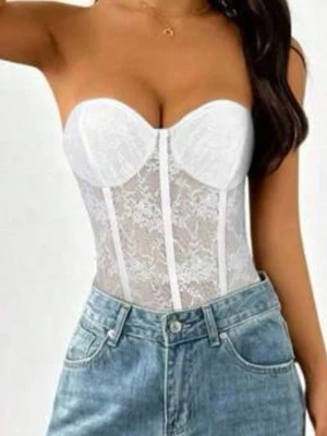 Vit spetskorsett med bygel - Trendig vit korsett body med bygel. Tillverkad i genomskinlig spets med dekorativa sömmar framtill. Axelbandslös modell som ger en snygg siluett och passar perfekt till jeans eller kjol. Aldrig använd