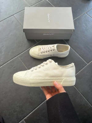 Gant sneakers - Snygga vita sneakers från Gant i klassisk låg modell. Skorna har en tjock sula, diskret Gant-logga på sidan och är tillverkade i canvasmaterial med gummidetaljer. Perfekta för en clean och stilren look till vardagsoutfiten.