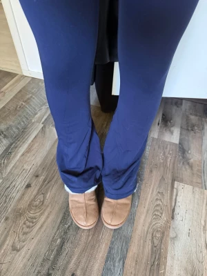 Mörkblå yoga pants med omlott-midja - Mörkblå yoga pants  med trendig omlott-midja och raka ben. Byxorna är i ett mjukt och stretchigt material som känns skönt mot huden. Perfekta för en avslappnad stil och passar till både chill och träning.