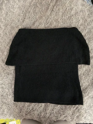 Svart off shoulder stickad topp Nelly - Säljer en svart stickad off shoulder topp från Nelly. Toppen har en bred, vikt kant upptill och är ribbstickad i mjukt material. Perfekt för dig som gillar trendiga och stilrena plagg med en twist.