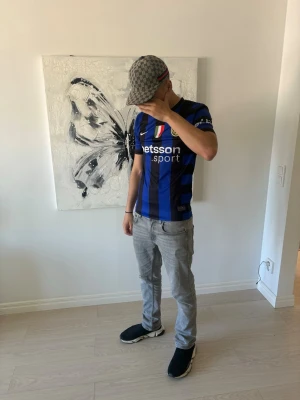 Inter Milan matchtröja Nike blå/svart - Säljer en Inter Milan matchtröja från Nike i blått och svart med vertikala ränder. Tröjan har klubbmärke, Nike-logga och sponsortryck på bröstet samt korta ärmar. Perfekt för dig som älskar fotboll och vill visa ditt stöd för laget.