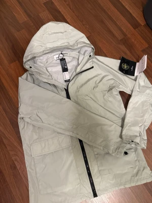 Ljusgrön/ mintfärgad vindjacka från Stone Island - Snygg ljusgrön/mint färgad vindjacka från Stone Island med huva och hel dragkedja framtill. Tillverkad i lätt  material som står emot vind och regn. Passar med både jeans, mjukis eller shorts på sommarkvällarna. Perfekt för en stil och färg som passar alla årstider. Kan tänka mig gå ner i pris vid snabb affär, notera att den är helt ny💪