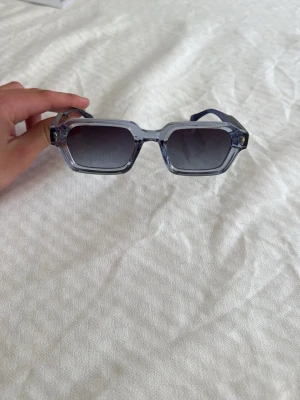 Visionair glasögon  - Snygga solglasögon med rektangulära bågar i transparent blå plast och mörka glas. Perfekta för att ge din outfit en cool touch. Bågarna har en modern design och sitter bekvämt på huvudet. Från visionair helt nya, nypris 499kr