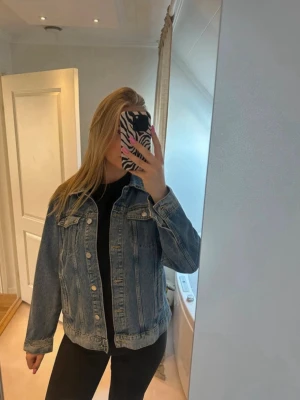 Klassisk blå jeansjacka från Lindex - Snygg blå jeansjacka från Lindex, använd en gång och är i nyskick, köptes förra våren men har inte kommit till användning 
