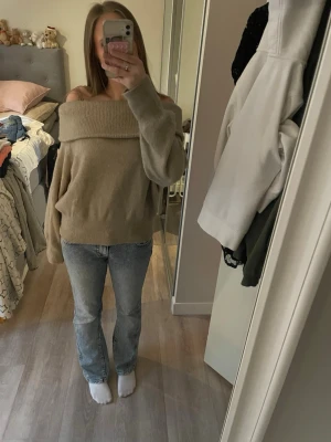 Beige off shoulder stickad tröja H&M - Snygg beige stickad tröja från H&M med bred off shoulder-krage. Tröjan har långa ärmar och ribbstickade muddar vid ärmslut och nederkant. Perfekt för lager-på-lager och chill höststil.
